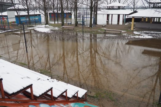 Sremska Mitrovica, Serbia 01.27.2023 Flooding on the Sava river. Deluge after rains and melting snow. Still muddy water on the beach. Reflection of tree trunks and branches in the water. Hydrology