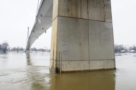 Sremska Mitrovica, Serbia, 01.27.2023 Bridge over the river Sava. Flooding after heavy rains and melting snow. A swift flow of muddy water. Hydrological scale for measuring the level of water