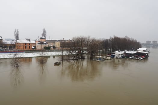 Macvanska Mitrovica, Serbia, 01.27.2023 The bridge over the Sava River. Flooding after heavy rains and snowmelt. A swift flow of muddy water. Trees, boats and piers in the water. Machva in winter