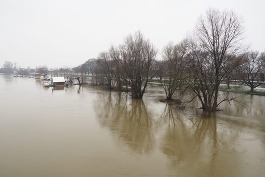 Macvanska Mitrovica, Serbia, 01/27/2023 The bridge over the Sava River. Flooding after heavy rains and snowmelt. A swift flow of muddy water. Trees, boats and piers in the water. Machva in winter
