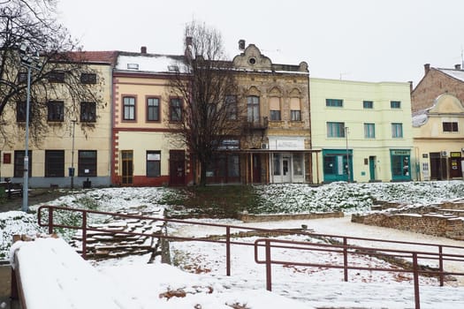 Sremska Mitrovica Serbia 01.27.2023 Snowfall in the city. Zhitni trg historical square. Ancient multi-colored buildings and excavations of Roman times. Weather forecast. Day winter. Cultural heritage