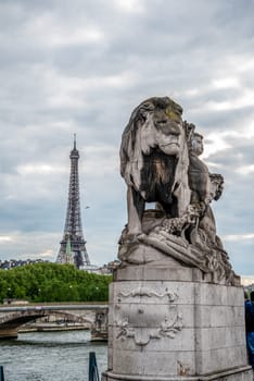 Statue of a Lioin on Bridge Alexandre III, view to Eiffel tower, Paris, France