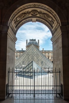 View through an Arch of the left wing of Louvre Palace to the Glass Pyramid, Paris, France