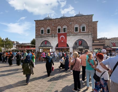 Istanbul, Turkey - August 30, 2022: Crowds of local citizens at Eminonu during the Victory Day holiday with entrance of The Spice Bazaar, aka Misir Carsisi, or Egyptian Bazaar in the background