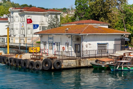 Kanlica Iskelesi, or Kanlica Ferry Terminal with background of dense green trees, white wooden buildings, and clear sky, in a summer day, located in Asian side of Bosphorus Strait, Istanbul, Turkey