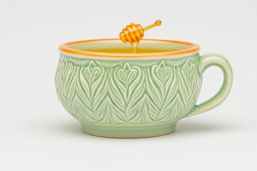 A delicately designed green cup holds warm liquid, while golden honey drizzles gently from a wooden dipper in an inviting ambiance.