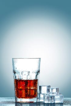 Glass of cola with ice cubes on a blue background