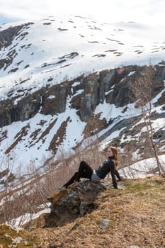 Mountains, snow-covered fjord, Girl sitting on the background of the valley. Norway in the spring