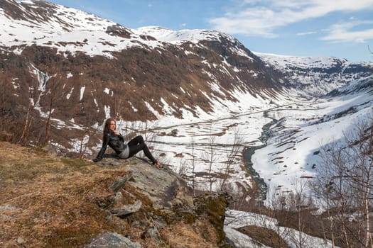 Mountains, snow-covered fjord, Girl sitting on the background of the valley. Norway in the spring
