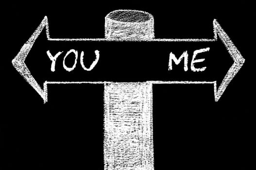 Opposite arrows with You versus Me. Hand drawing with chalk on blackboard. Choice conceptual image