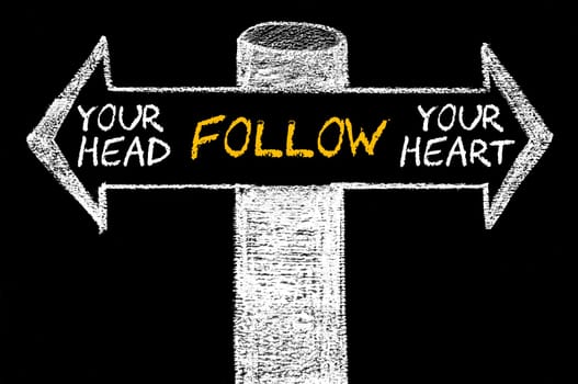 Opposite arrows with Follow Your Head or Your Heart. Hand drawing with chalk on blackboard. Choice conceptual image