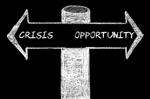 Opposite arrows with Crisis versus Opportunity. Hand drawing with chalk on blackboard. Choice conceptual image