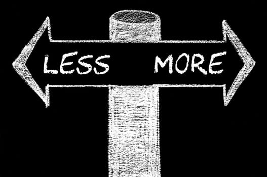 Opposite arrows with Less versus More. Hand drawing with chalk on blackboard. Choice conceptual image