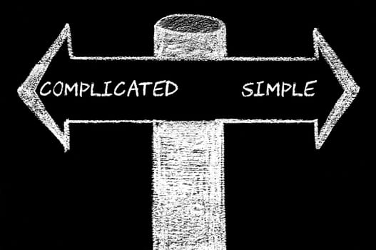 Opposite arrows with Complicated versus Simple.. Hand drawing with chalk on blackboard. Choice conceptual image