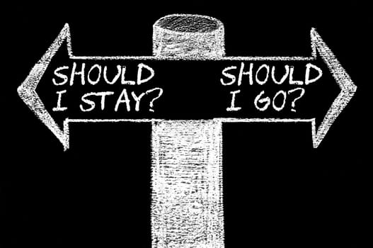Opposite arrows with Should I Stay versus Should I Go. Hand drawing with chalk on blackboard. Choice conceptual image
