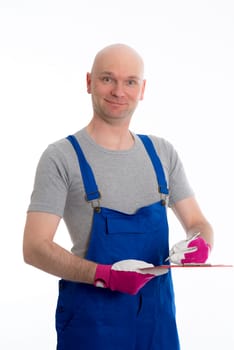 young workman in blue dungarees with clipboard in front of white background