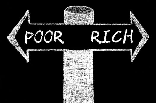 Opposite arrows with Poor versus Rich. Hand drawing with chalk on blackboard. Choice conceptual image