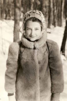 Portrait of a Soviet girl in a fur coat and a fur hat. Old vintage sepia photo taken in the USSR in the 1991