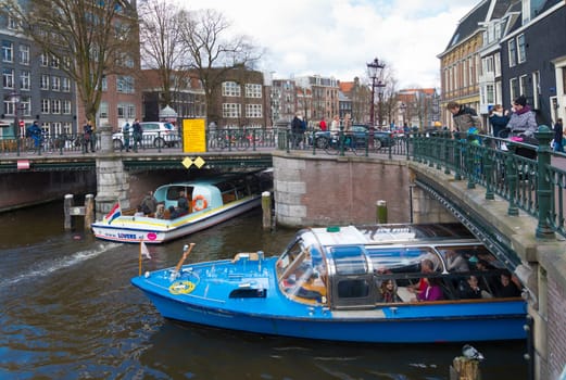 two sightseeing boats under a bridge in the amsterdam canals