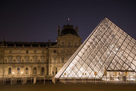 The famous Louvre Palace and its iconic glass pyramide at night, Paris, France