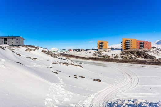 Greenlandic landscape with Inuit multistory houses of Nuuk city on the rocks with mountains in the background, Greenland