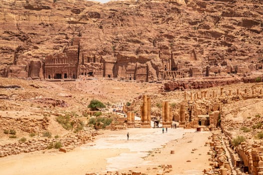 Petra main street with ancient Nabataean Royal tombs in the background and ruins of grand temple in the foreground, Petra, Jordan