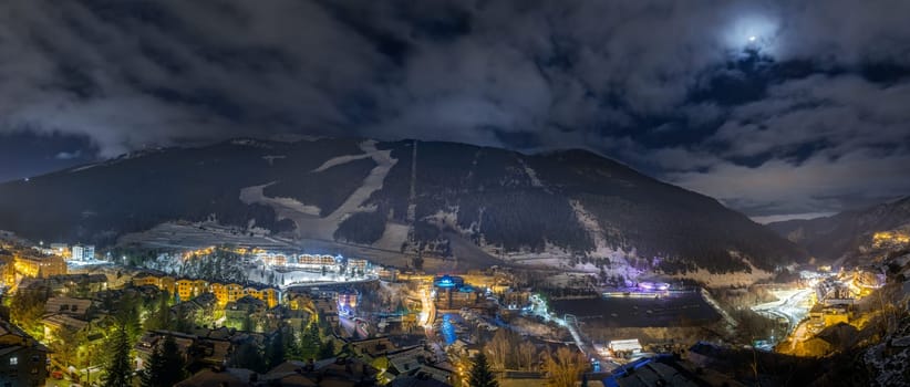 Panorama with El Tarter town. Hotels, resorts and residential buildings illuminated by street lights at night. Ski winter holidays, Andorra, Pyrenees