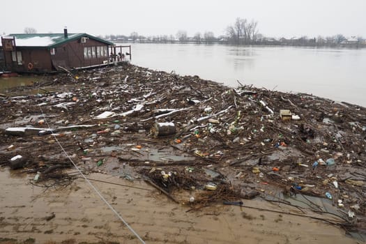 Sremska Mitrovica, Serbia, Balkans, 01.27.2023 Embankment of the Sava river. Garbage, plastic, toxic organic waste, bottles and windbreak in river water. Ecological problem. Environmental pollution