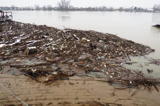 Sremska Mitrovica, Serbia, Balkans, 01.27.2023 Embankment of the Sava river. Garbage, plastic, toxic organic waste, bottles and windbreak in river water. Ecological problem. Environmental pollution