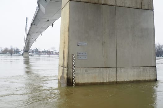 Sremska Mitrovica, Serbia, 01.27.2023 Bridge over the river Sava. Flooding after heavy rains and melting snow. A swift flow of muddy water. Hydrological scale for measuring the level of water
