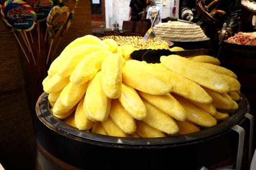 Eclairs in the form of yellow bananas on a dish. Showcase of candy store Dubrovnik Croatia. Delicious sweet cakes are displayed for sale to tourists. Unusual form of baking with powdered yellow sugar