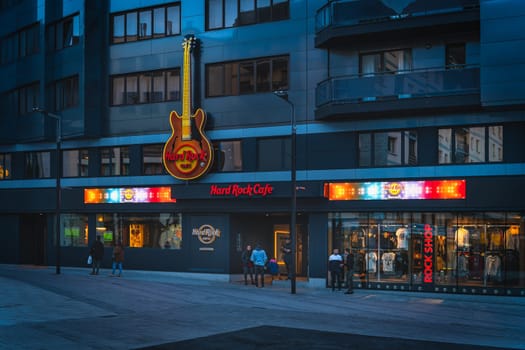 Andorra la Vella, Jan 2020 People at Hard Rock Caffe with big neon guitar and shop display in capital city of Andorra, Pyrenees Mountains