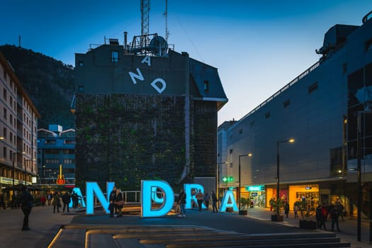 Andorra la Vella, Jan 2020 People taking pictures of iconic neon letters forming sign Andorra at night, Pyrenees Mountains