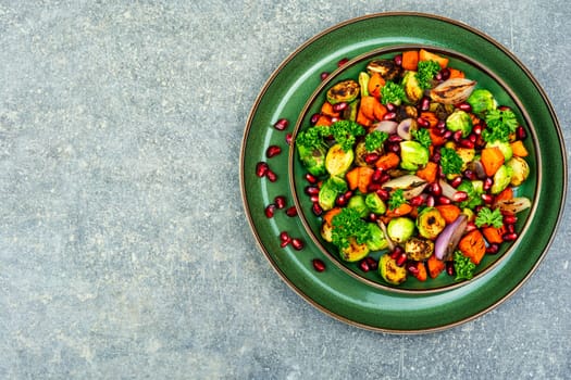 Salad with grilled brussels sprouts, grilled carrots, decorated with greens and pomegranate. Copy space, vegan menu