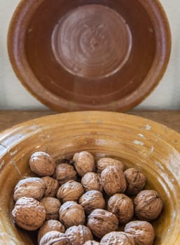 Glazed clay platter full of walnuts. Selective focus