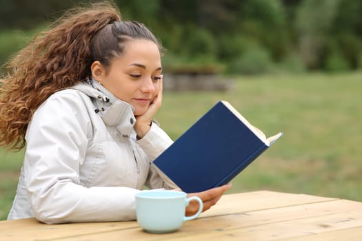 Hiker reading a book in a table in the mountain