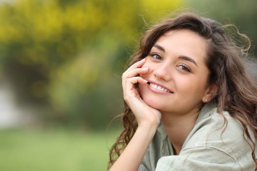 Portrait of a beautiful woman smiling at you in a park