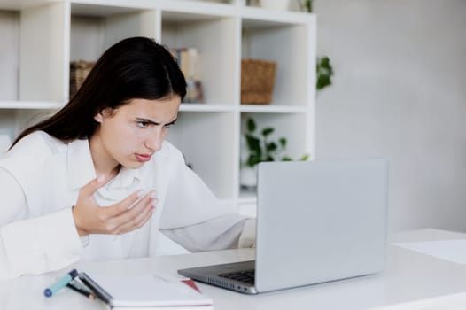 Angry young woman at home office desk work online on computer, have problems with device. Unhappy confused female distressed with laptop troubles, looks desperately, credit card issues while shopping