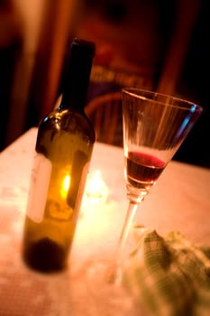 An empty wine bottle and wine glass on a table.