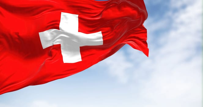 Close-up view of the swiss national flag waving in the wind. Switzerland is a landlocked country located in Europe. Fabric textured background. Selective focus