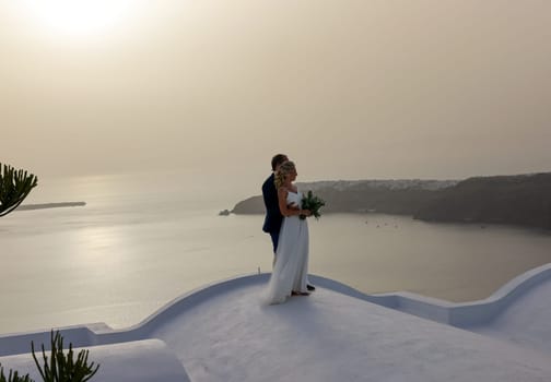 Imerovigli, Santorini, Greece - July 1, 2021: The bride and groom during a romantic photo session in Imergovigli on Santorini Island.