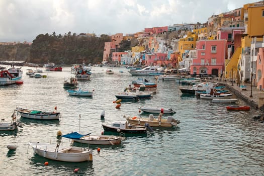 View of the Port of Corricella with lots of colorful houses on a sunny day in Procida Island, Italy.