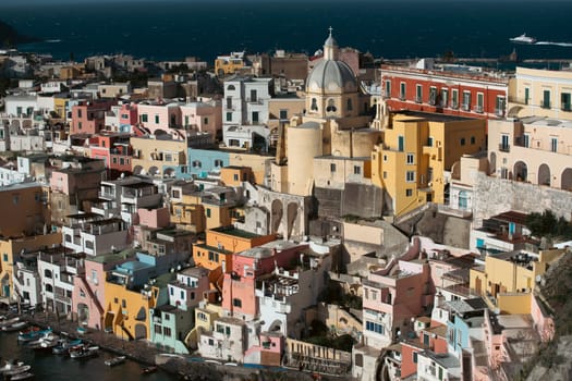 View of the Port of Corricella with lots of colorful houses on a sunny day in Procida Island, Italy.