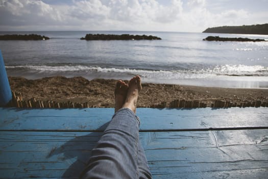 Closeup photo of women's legs on the blue wooden pier over the sea, summer vacation concept