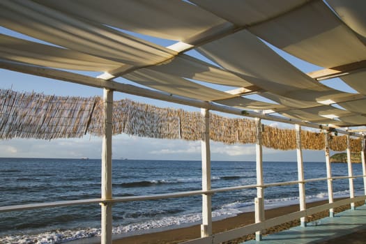 Cozy terrace on the beach, idyllic view of the seashore. Tropical summer vacation concept.