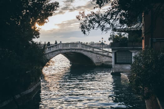 Venice, Italy, November 2014: One of the many bridges over a canal in Venice during sunset.