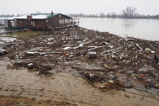 Sremska Mitrovica, Serbia, Balkans, 01.27.2023 Embankment of the Sava river. Garbage, plastic, toxic organic waste, bottles and windbreak in river water. Ecological problem. Environmental pollution