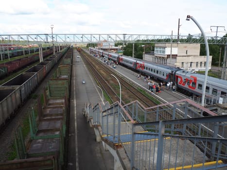 Svir, Russia, August 6, 2021. Railway station top view. People get off the trains. District railway station of the Oktyabrskaya railway. Docking station for two types of electric traction.