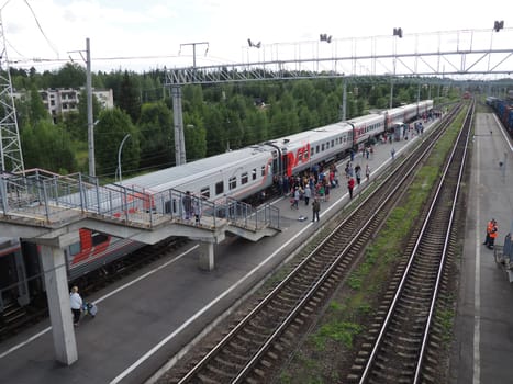 Svir, Russia, August 6, 2021. Railway station top view. People get off the trains. District railway station of the Oktyabrskaya railway. Docking station for two types of electric traction.