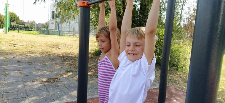 Sremska Mitrovica, Serbia, September 13, 2020. A boy and a girl on the sports or playground are engaged in physical exercise. Child in a white t-shirt.